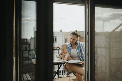 Mother relaxing with baby on balcony in summer