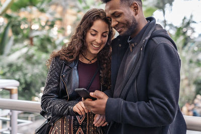 Smiling couple looking at phone while walking outdoors