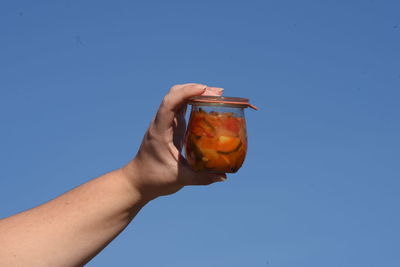 Midsection of man holding ice cream against blue sky