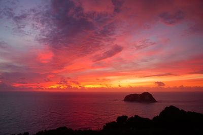 Scenic view of sea against dramatic sky during sunset