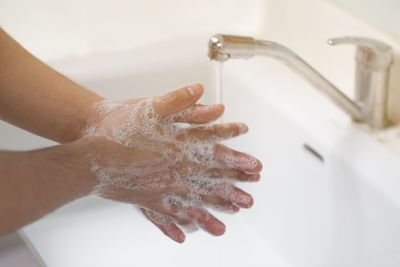 Close-up of hand touching water in bathroom