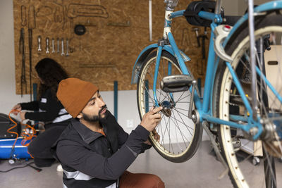 Male technician repairing bicycle wheel in workshop at recycling center