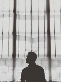 Rear view of silhouette man standing by window