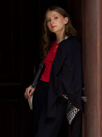 Portrait of young woman standing against wall