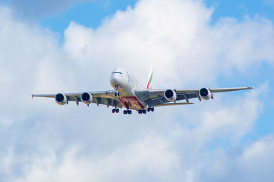 Low angle view of airplane flying against cloudy sky