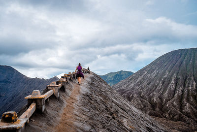 Rear view of woman walking on mountain against sky