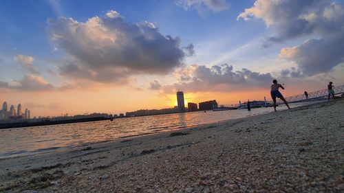 People on beach against sky during sunset