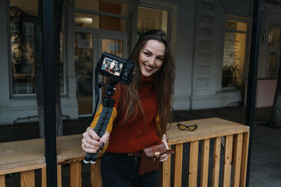 Portrait of smiling young woman holding camera