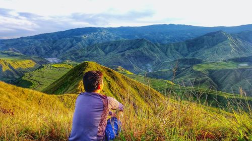 Rear view of boy sitting on mountain at panimahawa ridge