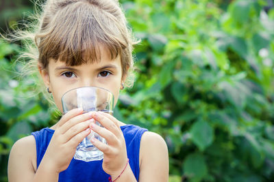 Portrait of young woman drinking water in yard