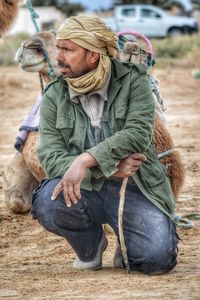 Man with camel sitting outdoors