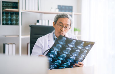 Senior male doctor analyzing x-ray at desk in hospital