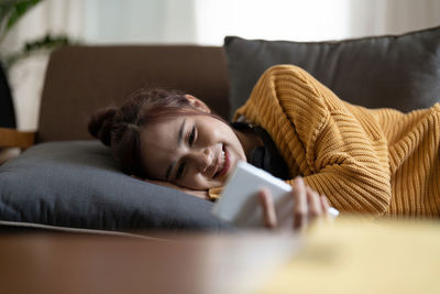 Portrait of young woman lying on bed at home