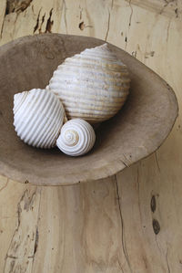 Close-up of seashells in bowl on wooden table