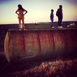People standing on land against sky during sunset
