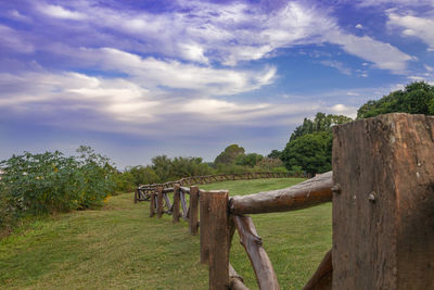 Wooden fence on field against sky