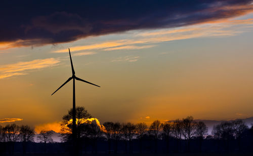 Low angle view of wind turbines during sunset