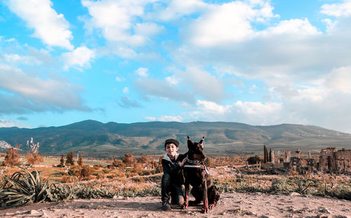 Portrait of boy with dog sitting on field