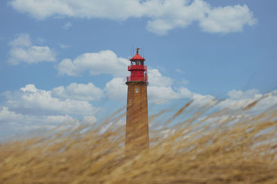 Lighthouse on beach against sky