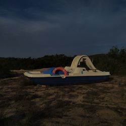 Boat moored on land against sky