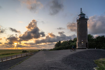 Road by lighthouse against sky during sunset