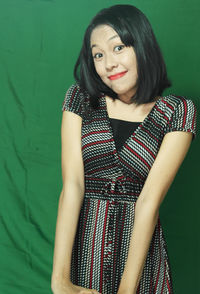 Portrait of smiling woman standing against green wall