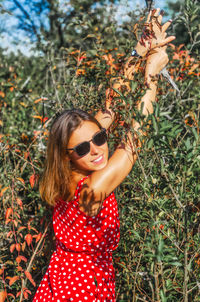 Pretty woman in sunglasses with branches with black berries in her hands.