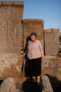 Portrait of old woman standing against wall