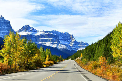 Road amidst trees and mountains against sky