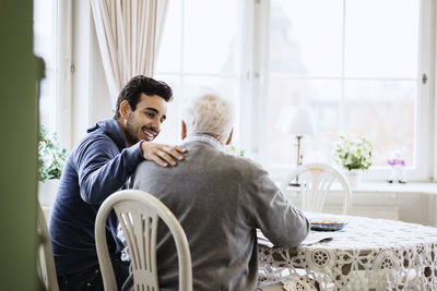 Happy caretaker communicating to senior man in nursing home