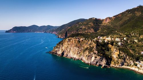 Scenic view of sea and mountains against clear blue sky