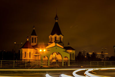 Light trails on road against illuminated church at night
