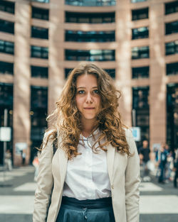 Portrait of beautiful young woman standing in city