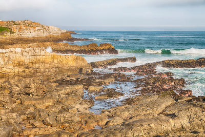 Rock formation on beach against sky