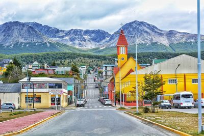 Road amidst buildings and mountains against sky