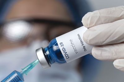 Cropped hand of doctor holding syringe with vial