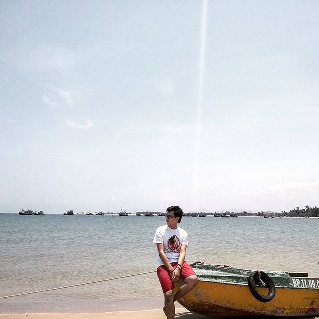 water, sea, mode of transport, lifestyles, transportation, leisure activity, nautical vessel, rear view, full length, casual clothing, sky, beach, sitting, nature, horizon over water, boat, shore, day