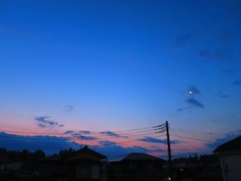 Silhouette houses against sky at sunset