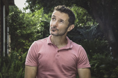 Young man looking away while standing outdoors