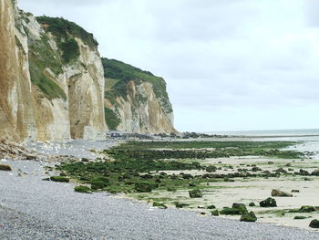 Scenic view of cliff by sea against sky