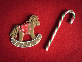 Close-up of animal shaped gingerbread cookie and candy cane on red fabric