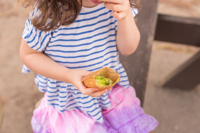 Midsection of girl earing food while sitting at park