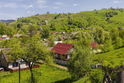 House and trees on landscape against sky