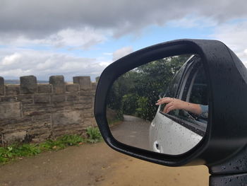 Close-up of hand on side-view mirror of car