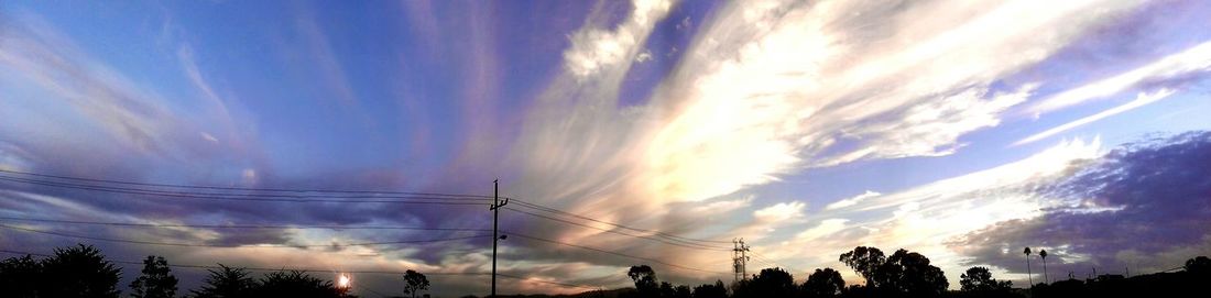 Low angle view of power lines against cloudy sky