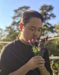 Low section of person holding red flowering plant