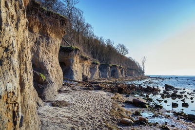 Rock formation on beach against clear sky