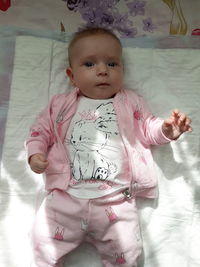 High angle portrait of cute baby girl lying on bed at home