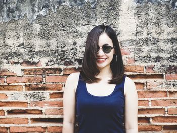 Portrait of smiling young woman against wall