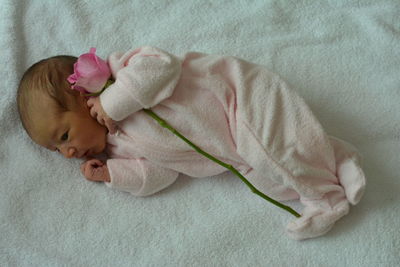 Directly above shot of baby with rose on bed at home